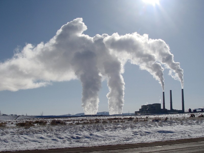 Smokestacks in the distance against a grey-blue sky billow white smoke.